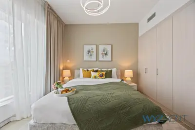 a bedroom with a large bed with a green blanket at 2BR Aegean Charm Sulafa Tower, Canal View & Gym in Dubai