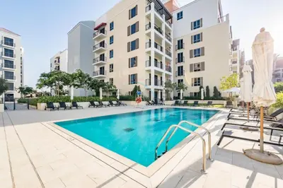 a swimming pool with chairs and a building at Seafront 2BR, Within Walking Distance to La Mer Beach, Short Drive Away from Mercato Mall, La Sirene Building 2, La Mer by Deluxe Holiday Homes in Dubai