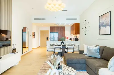 a living room and kitchen with a couch and a table at Seafront 2BR, Within Walking Distance to La Mer Beach, Short Drive Away from Mercato Mall, La Sirene Building 2, La Mer by Deluxe Holiday Homes in Dubai