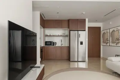 a kitchen with wooden cabinets and a stainless steel refrigerator at Stylish 2BR Beachfront Pool&Gym Access in Dubai