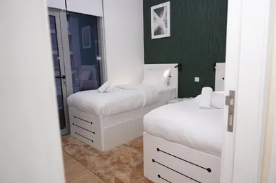 a bedroom with two beds and a green wall at Stylish Marina Stay Near Bla Bla club & JBR Walk in Dubai