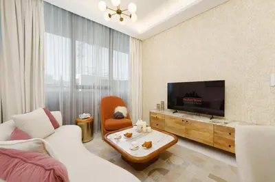a living room with a television and a couch and chair at Private Pool Stylish 1BR Arjan in Dubai