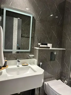 a bathroom with a sink and a mirror and a toilet at Private Pool Stylish 1BR Arjan in Dubai
