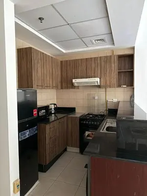 a kitchen with wooden cabinets and a black refrigerator at Luxury Stay - Walk to Dubai Mall & Burj Khalifa 21 in Dubai