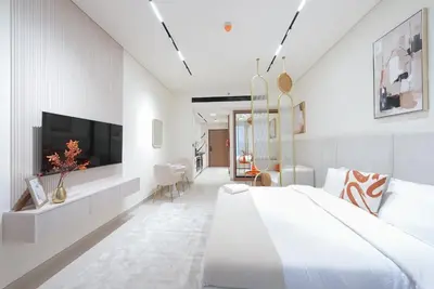 a white bedroom with a large bed and a tv at Designer Studio Retreat with Jacuzzi & Canal Views in Dubai