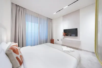 a white bedroom with a large bed and a tv at Designer Studio Retreat with Jacuzzi & Canal Views in Dubai