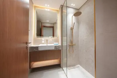 a bathroom with a sink and a glass shower at Designer Studio Retreat with Jacuzzi & Canal Views in Dubai