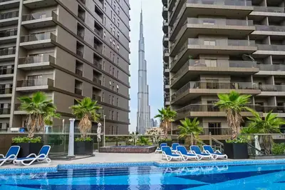 a pool with chairs and palm trees in front of buildings at Front Burj View - 6min to Dubai Mall - Pool - Gym in Dubai