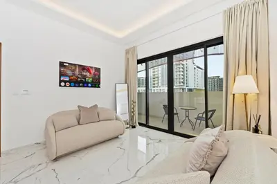 a white living room with a couch and a table at Riviera Azure Gateway Superior- 10min to Burj Khalifa, Dubai Mall and Airport and 20min to Marina in Dubai