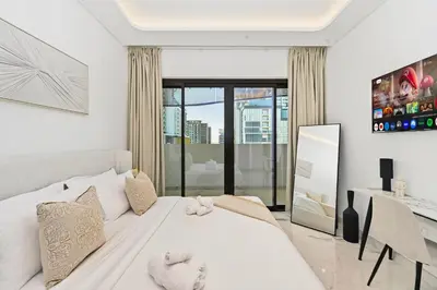 a bedroom with a white bed and a desk at Riviera Azure Gateway Superior- 10min to Burj Khalifa, Dubai Mall and Airport and 20min to Marina in Dubai