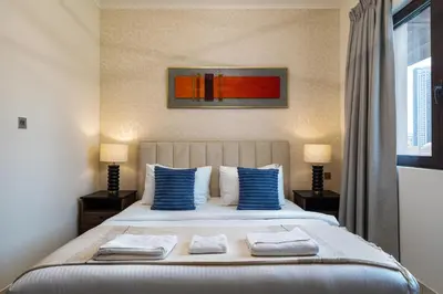 a bedroom with a large bed with blue pillows at Theatre Room - Pool Access - Central 2br Apartment in Dubai