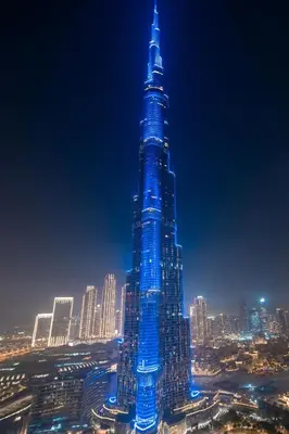 a tall skyscraper lit up in blue at night at Frank Porter - Burj Vista Tower 1 in Dubai