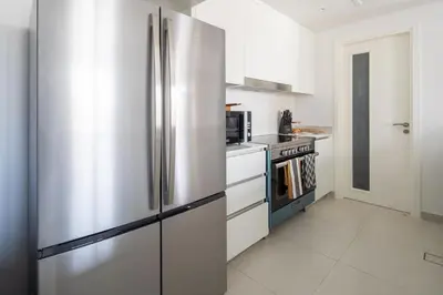 a stainless steel refrigerator in a white kitchen at Frank Porter - Jadeel 3 in Dubai