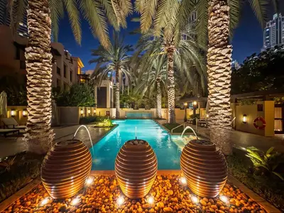 a swimming pool with palm trees and a hotel at GuestReady - 2BR | Downtown Bliss with Burj View in Dubai
