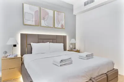 a white bedroom with a large bed with white pillows at Stylish 1BR Villa near Global Village and Golf Clubs in Dubai