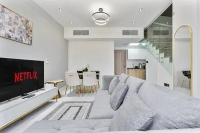 a living room with a couch and a tv at Stylish 1BR Villa near Global Village and Golf Clubs in Dubai