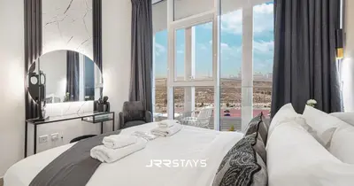 a bedroom with a large white bed with a large window at Stylish Luxury 1BR - Modern Design - JVC in Dubai