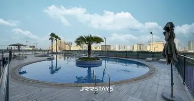 a large swimming pool with a tree in it at Stylish Luxury 1BR - Modern Design - JVC in Dubai