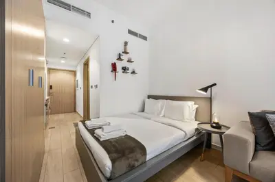 a white bedroom with a bed and a chair at Elite Escape - Stylish Getaway in Azizi Riviera 43 in Dubai