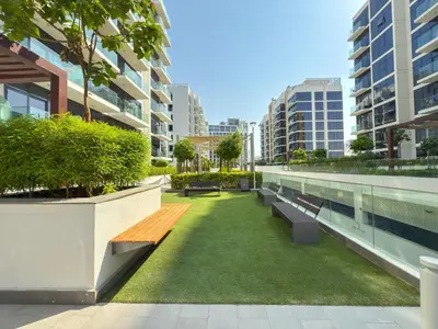 a park with benches and grass in a city at Elite Escape - Stylish Getaway in Azizi Riviera 43 in Dubai