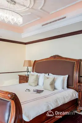 a bedroom with a wooden bed with white pillows at Dream Inn - Timeless Arabic-Inspired Penthouse with Private Pool and Sweeping Ain Dubai Views in Dubai