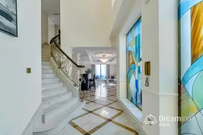 a hallway with white stairs and colorful paintings on the walls at Dream Inn - Timeless Arabic-Inspired Penthouse with Private Pool and Sweeping Ain Dubai Views in Dubai