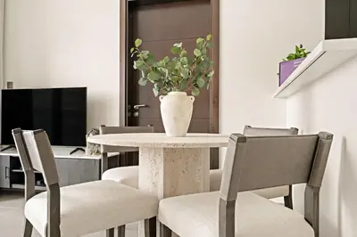 a table with chairs and a vase with a plant on it at Silkhaus Modern 2BR in Merano Tower in Business Bay in Dubai