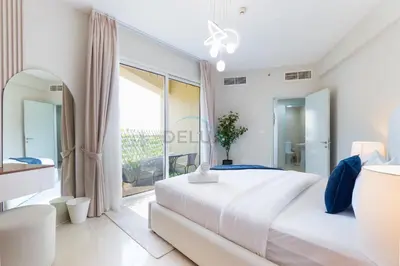 a white bedroom with a large bed and a balcony at Balcony Offering Captivating Lake Views 1BR, Just a Hop from the Golf Course, Lakeside B, Dubai Production City by Deluxe Holiday Homes in Dubai