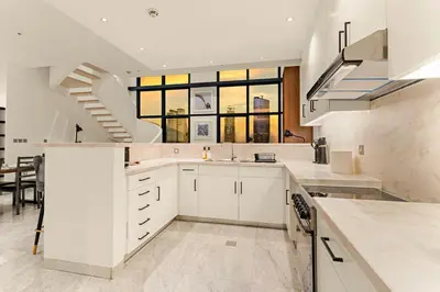 a kitchen with white cabinets and a large window at FIRST CLASS 2BR Elegant Duplex Haven in Dubai