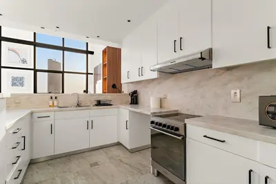 a kitchen with white cabinets and a large window at FIRST CLASS 2BR Elegant Duplex Haven in Dubai