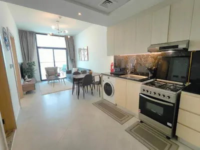 a kitchen with a stove and a table with chairs at Cozy Modern 1BR with Dubai Skyline View in Dubai