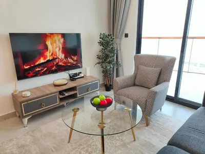 a living room with a tv and a chair at Cozy Modern 1BR with Dubai Skyline View in Dubai