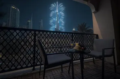 a table and chairs on a balcony with palm trees at Full Burj View - Souk vibe one-bedroom apartment in Dubai