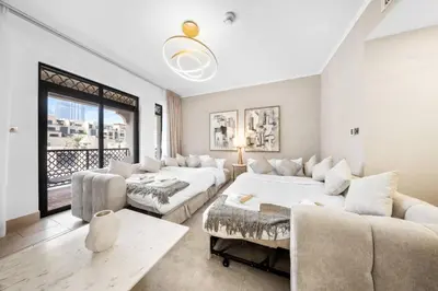 a living room with two beds and a couch at Full Burj View - Souk vibe one-bedroom apartment in Dubai