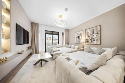 a living room with a large couch and a tv at Full Burj View - Souk vibe one-bedroom apartment in Dubai