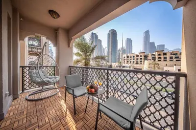 a balcony with chairs and a table and a city skyline at Full Burj View - Souk vibe one-bedroom apartment in Dubai