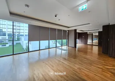 a large room with a wooden floor and large windows at Luxury 1BR in Sobha Hartland w Pool & Gym Access in Dubai