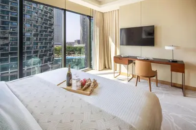 a bedroom with a bed and a desk and a large window at Frank Porter - Address Opera Tower in Dubai