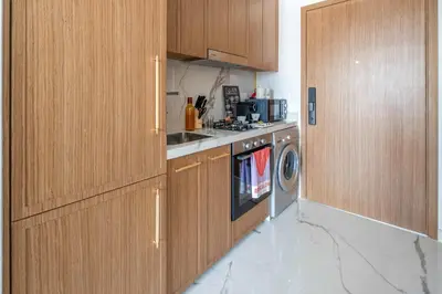 a kitchen with wooden cabinets and a washing machine at Frank Porter - Azizi Riviera 51, Meydan in Dubai
