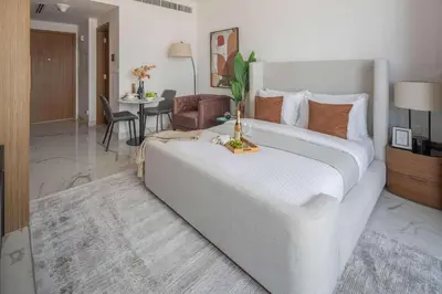 a bedroom with a large white bed and a living room at Frank Porter - Azizi Riviera Azure, Meydan in Dubai