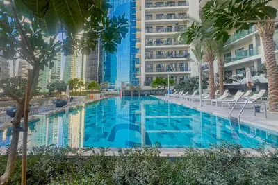 a large swimming pool with palm trees and buildings at Zada Tower, Business Bay - 1 Bedroom - Allsopp & Allsopp in Dubai