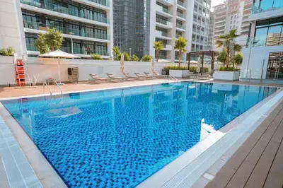 a large swimming pool with chairs in a building at NEW! Studio in Azizi Riviera 59 in Dubai