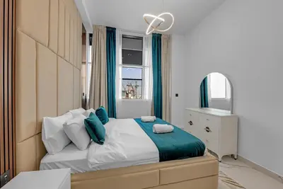 a bedroom with a bed with blue pillows and a window at Opal by Danube | Designer 1BR | Private Jacuzz in Dubai