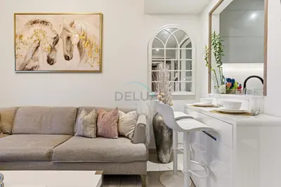 a living room with a couch and a kitchen at Creek Harbour Views 1BR, Just Minutes from Ras Al Khor Wildlife Sanctuary and Short Stroll to Zabeel Stadium, Binghatti Creek, Al Jaddaf by Deluxe Holiday Homes in Dubai