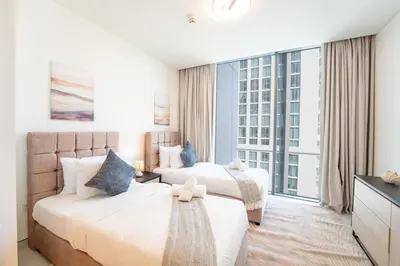 two beds in a hotel room with a large window at EasyGo - Stylish 2BR With City View in Sobha Creek in Dubai
