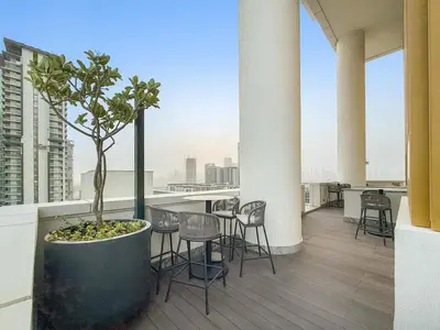 a balcony with chairs and a potted tree on a building at FIRST CLASS 3BR Stylish Luxury Escape in Dubai