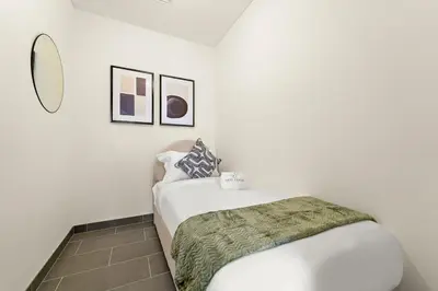 a white bedroom with a bed and a mirror at FIRST CLASS 3BR Trendy Luxe Getaway in Dubai