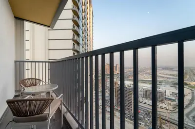 a balcony with two chairs and a view of a city at FIRST CLASS 3BR Trendy Luxe Getaway in Dubai