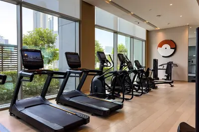a gym with treadmills and ellipticals in a room with windows at Dubai Mall access Vida Stunning Design in Dubai