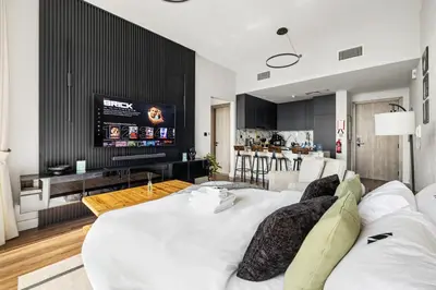 a living room with a large white bed and a tv at New 1BR with Rooftop Pool and Amazing View in Dubai